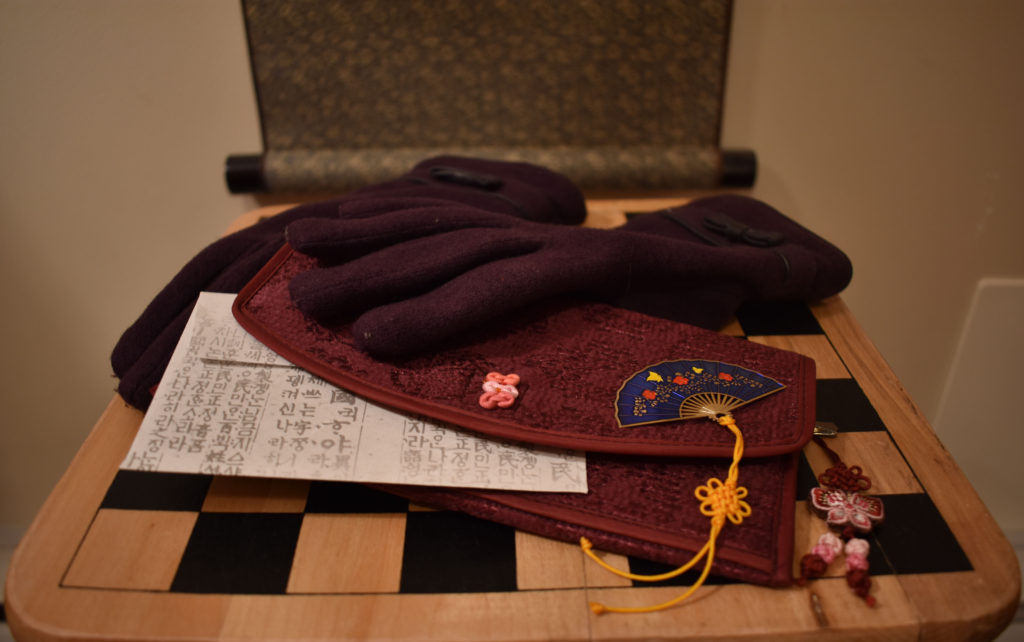 South Korean gloves, wallet, bookmark, and envelop rest on a chessboard. 
