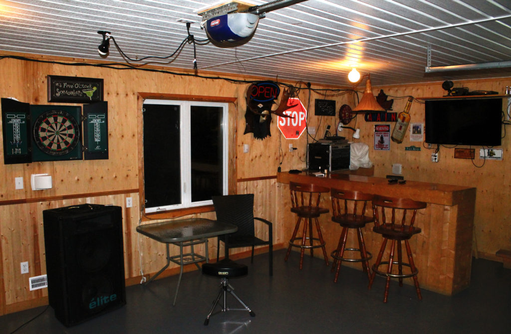 Wooden shed with signs on the wall. Bar and bar stools set up. 