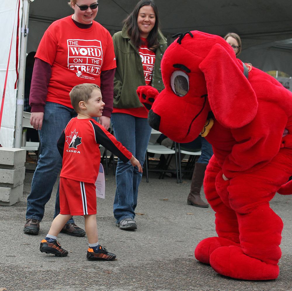 Cormac Fairweather gives Clifford the Big Red Dog a high five uring the Word on the Street Festival in Lethbridge, Alberta.