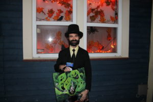 Man holding halloween bag in front of decorations. 