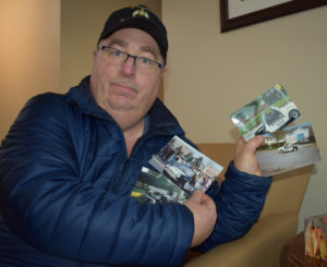 Noble David Pike displays his photographs of Hubert Locke driving his double-ended Keystone Kop car during a summer parade. Locke is sitting closest to the car’s engine dressed in a Kop outfit.