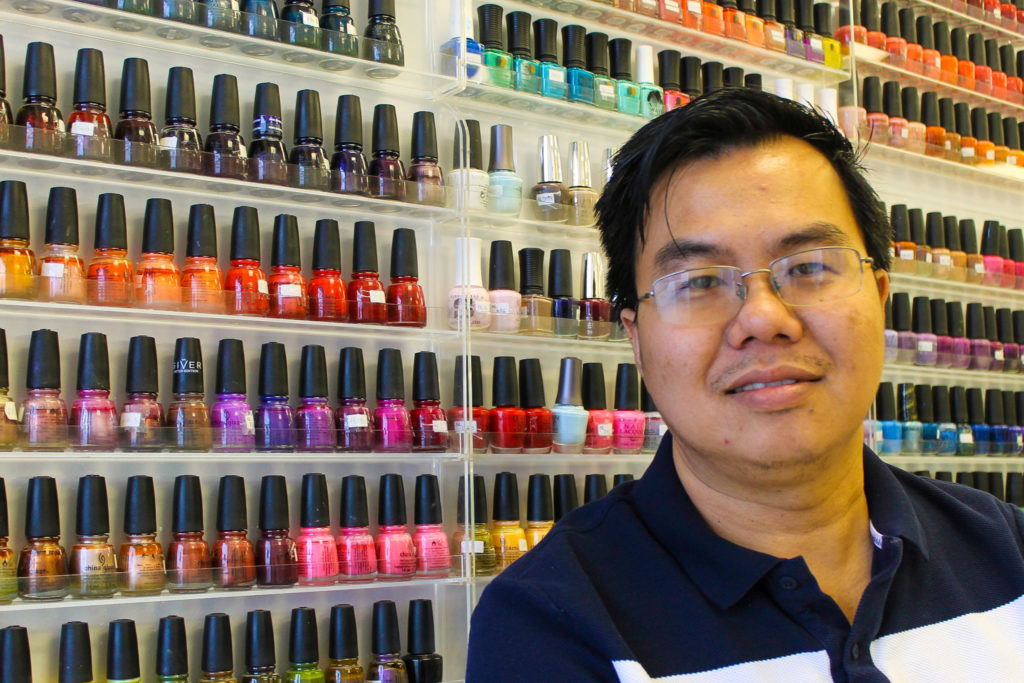 Kevin Le poses in front of the nail polish collectio