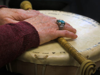 Marie Eastman's hands crossed over her personal drum, donned with hieroglyphs.