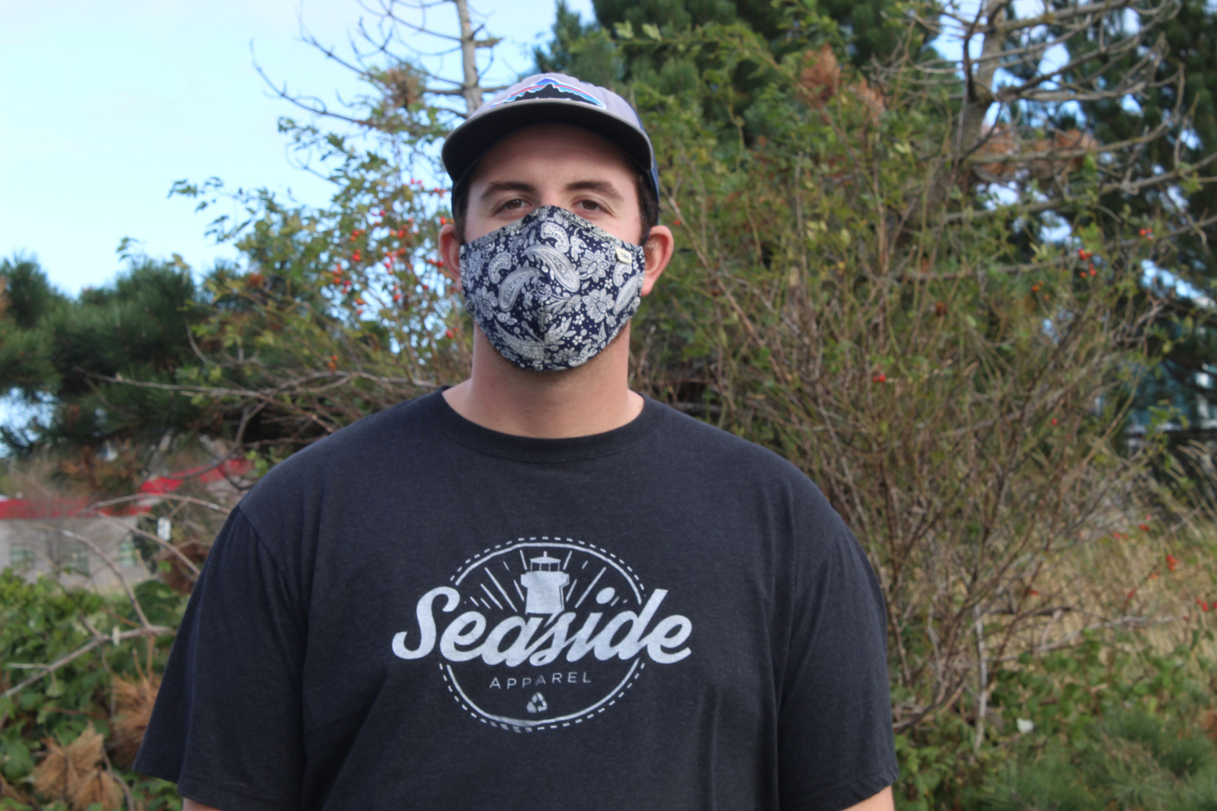 Trevor Bessette, owner of Seaside Reclaimed, standing in a park wearing a mask.