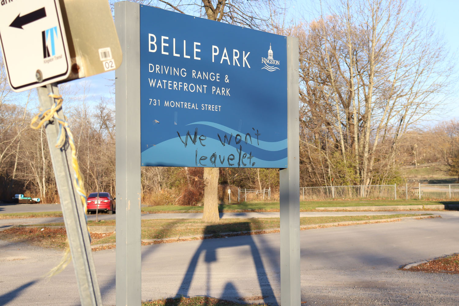 Image of Belle Park where people experiencing homelessness lived in the summer. The words "we won't leave yet" has been written on the sign.