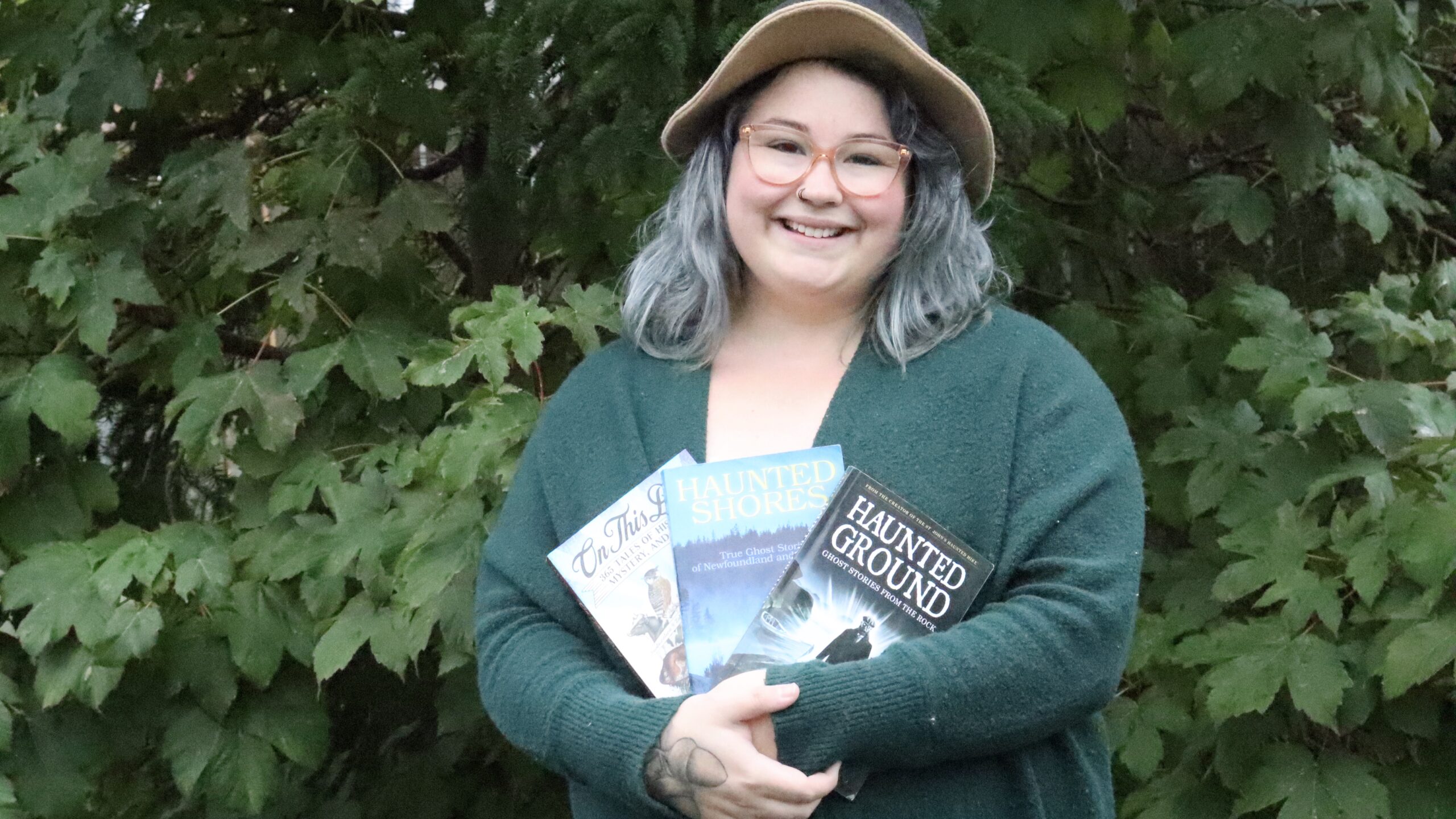Ashley DeMoss stands with her collection of ghost tale books by Dale Jarvis, founder of the Haunted Hike.