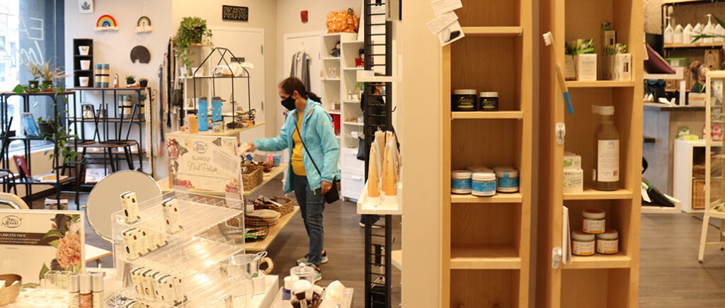 A shopper wearing a blue jacket and black mask browses nearly empty shelves in Winnipeg's Generation Green store. Half empty shelves sit in the foreground.