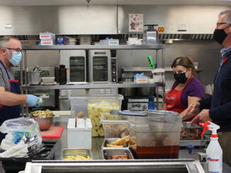 Volunteers of The Gathering Place work in the kitchen to prepare meals for adults in need of basic supports