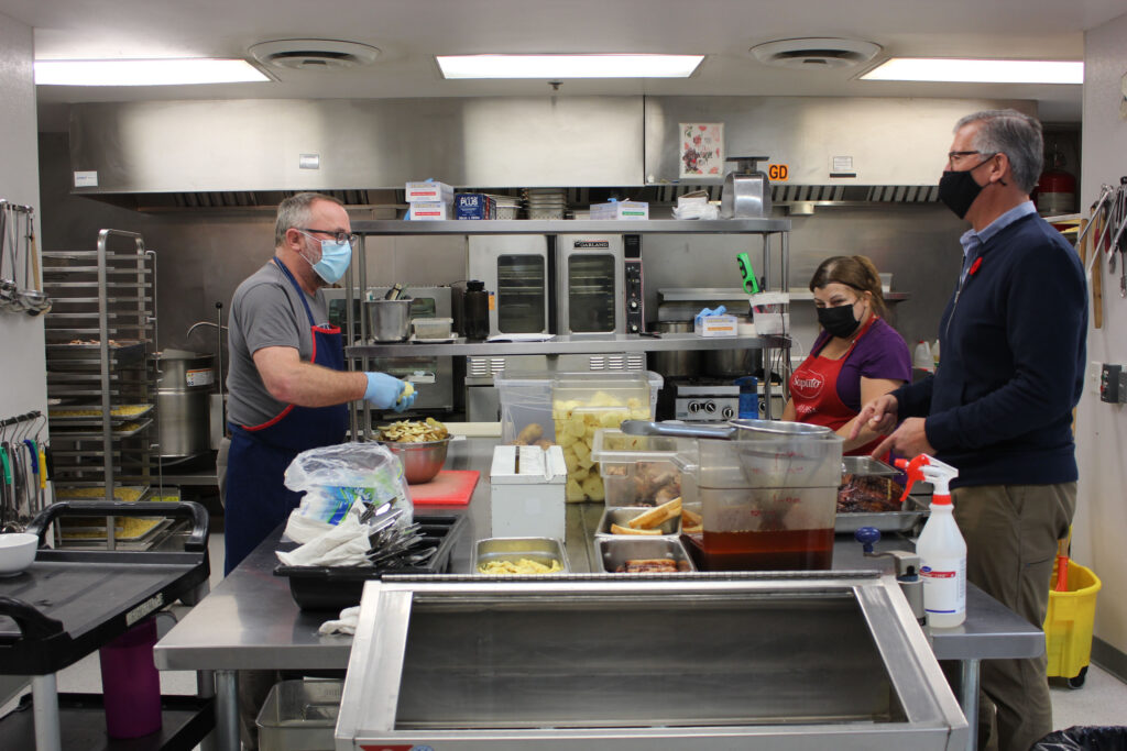 Staff of The Gathering Place work in the kitchen to prepare meals for adults in need of basic supports