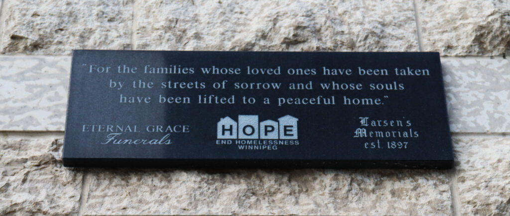 Black stone plaque with the words: For the families whose loved ones have been taken by the streets of sorrow and whose souls have been lifted to a peaceful home"
