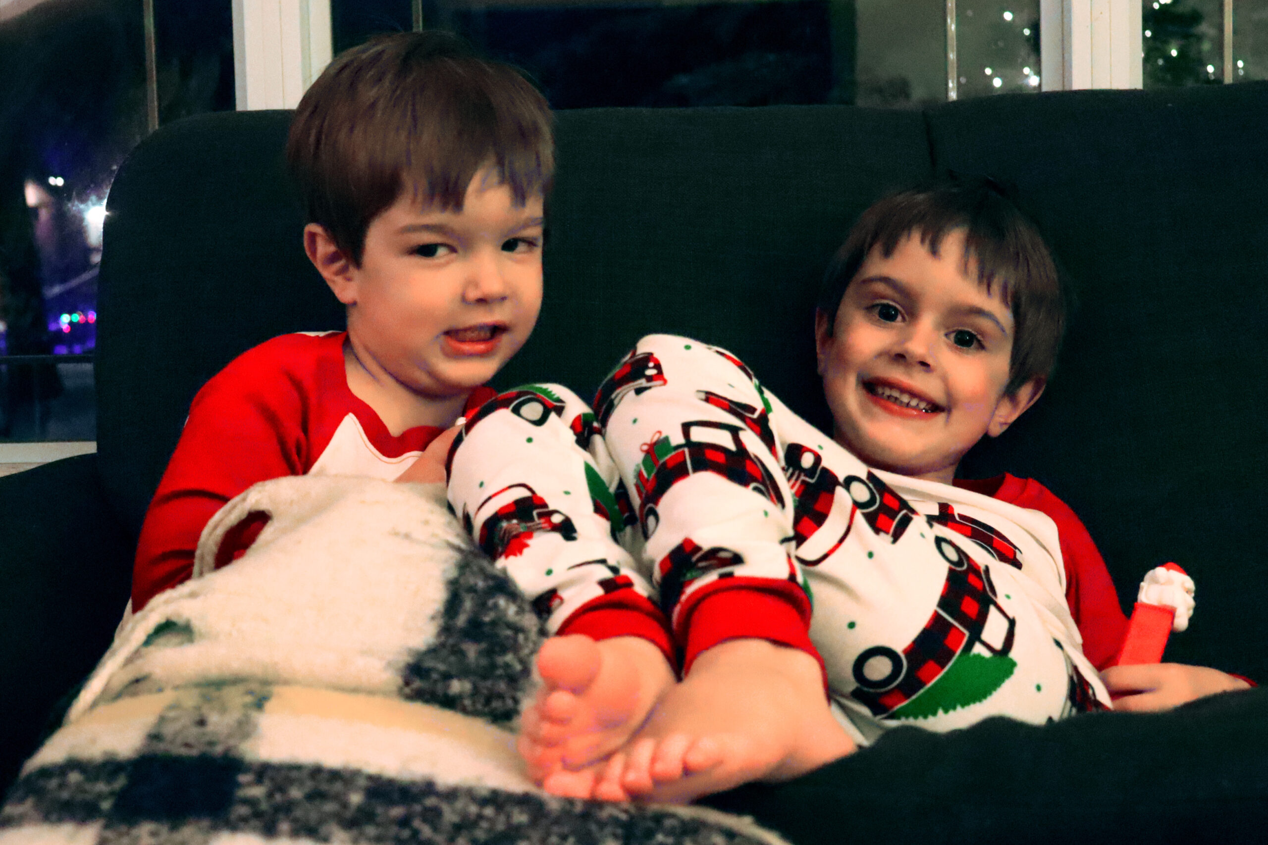 Two boys in Christmas pjs smile for the camera