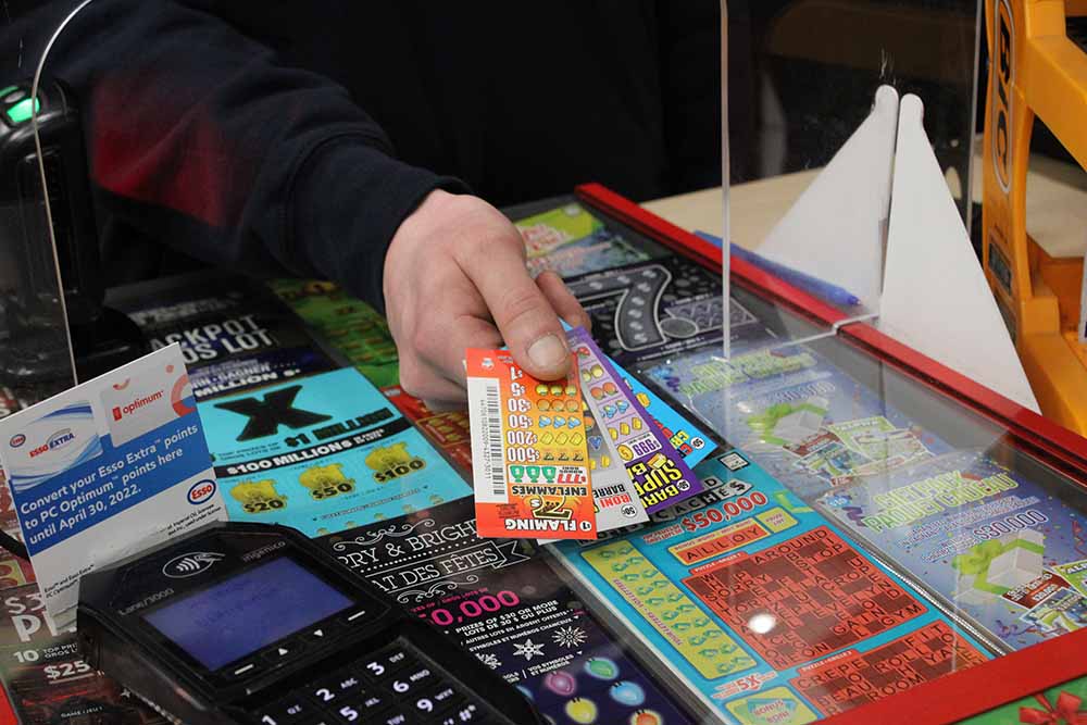 A gas station clerk sells a small stack of Nevada pull-tab lottery tickets against a backdrop of multi-coloured scratch tickets.