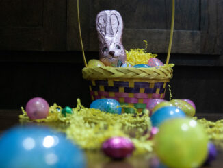 A trail of brightly coloured eggs lead to the Easter Bunny sitting in a basket.