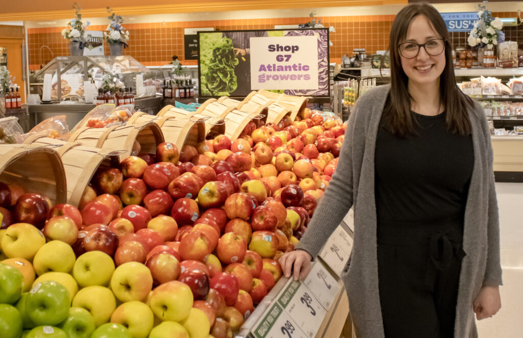 Heidi Murphy, a registered dietitian with Dominion, standing beside of the fruit session with a smile on her face.