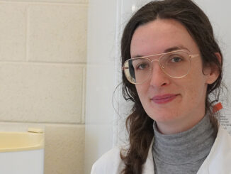 Jessica Melvin, a manger at the Civic Laboratory for Environmental Action Research, wearing white lab coat and laboratory goggles talking about microplastic study.