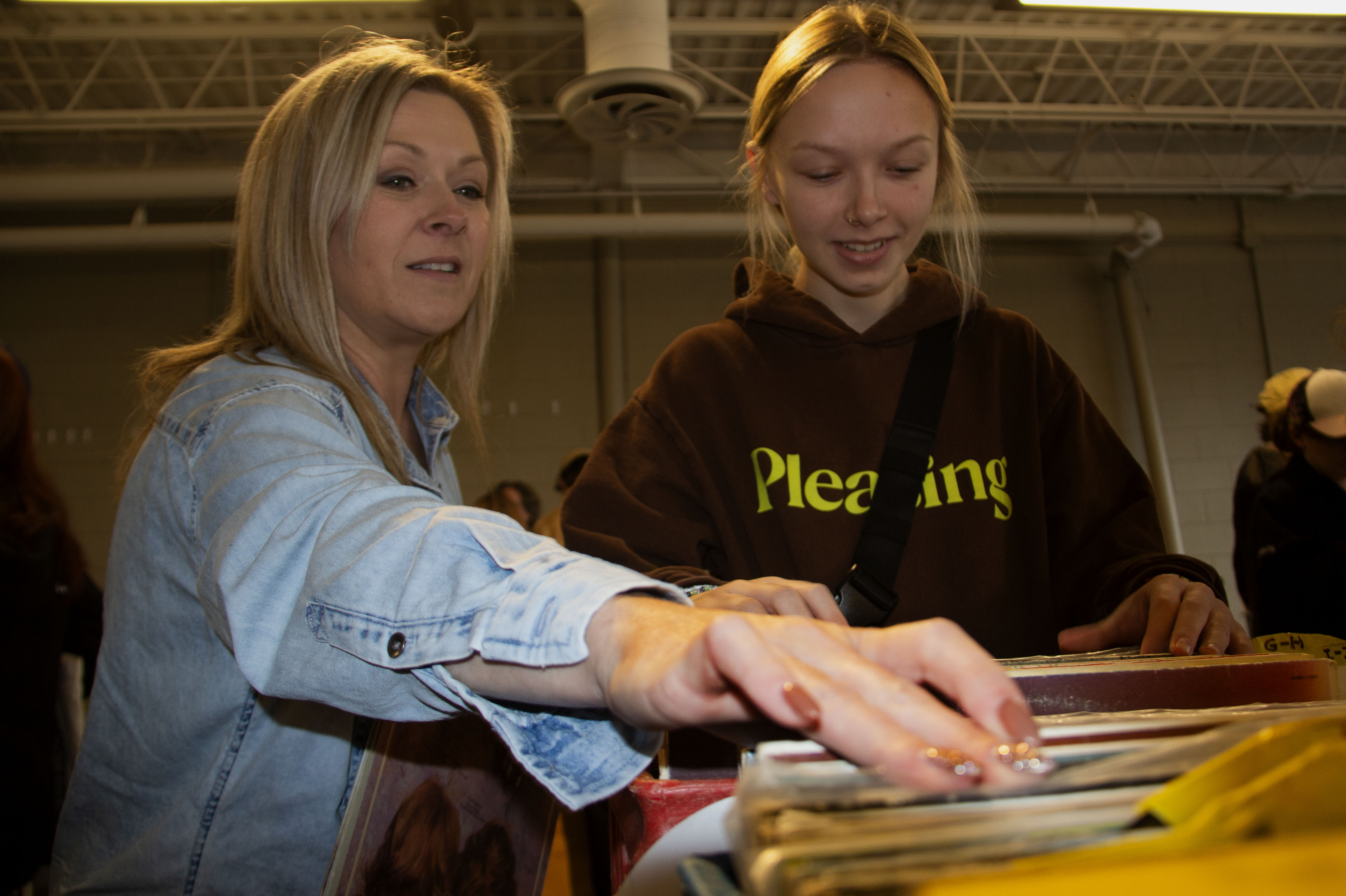 A mother and daughter pick through a crate or vinyl records.
