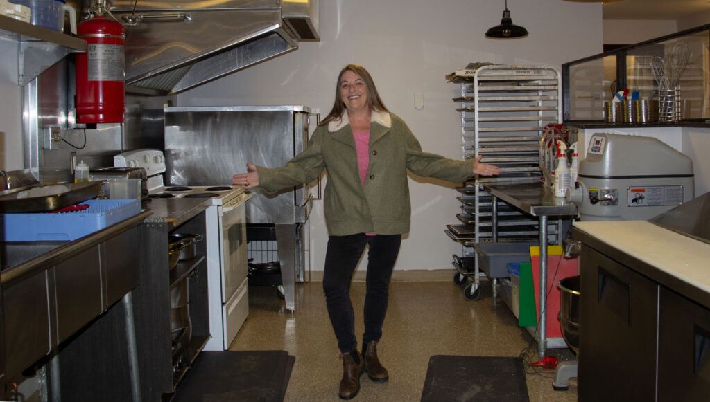 A woman stands proudly in a kitchen.