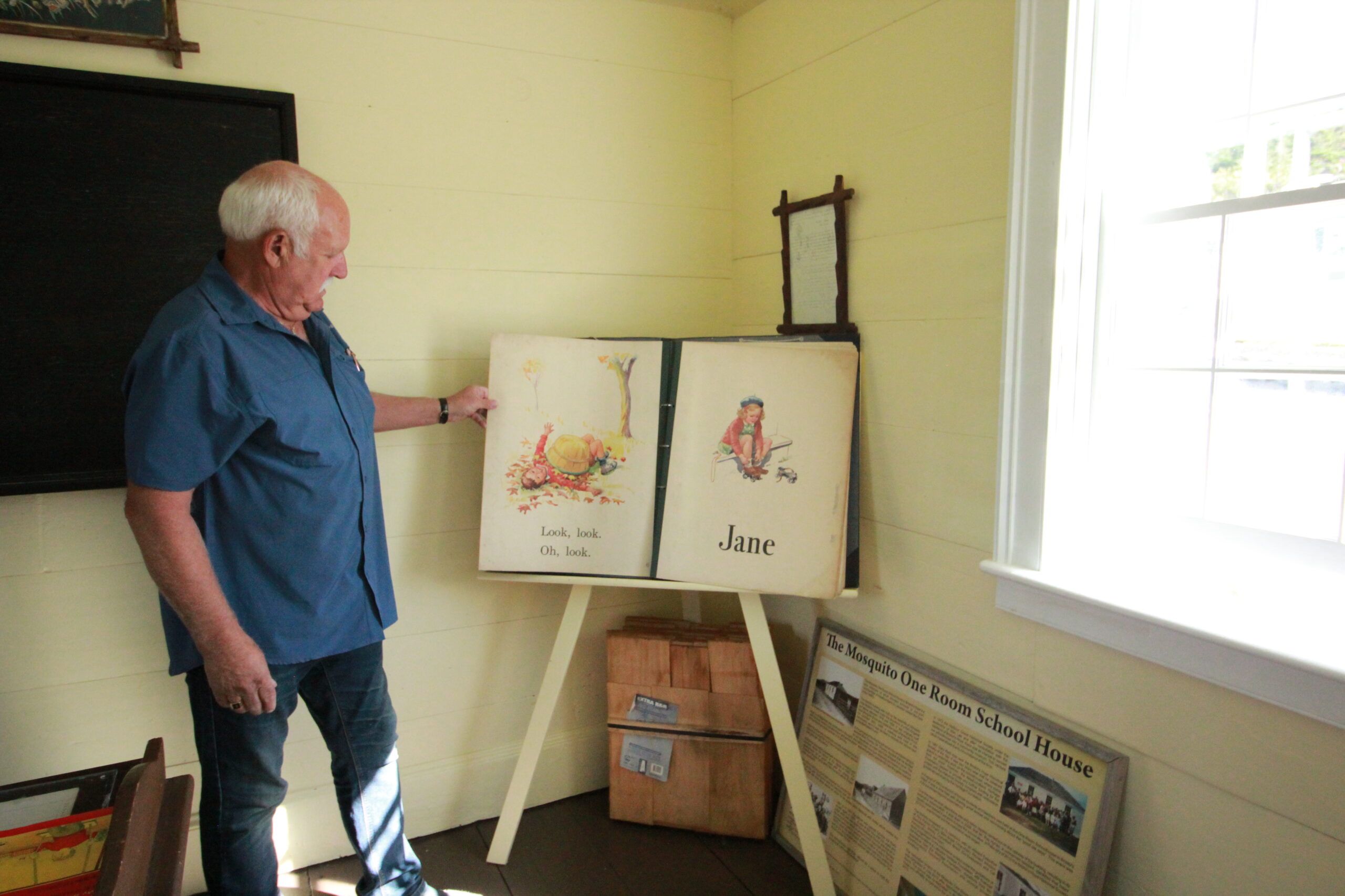 Richard Johnson flips through an old school book, Dick and Jane, used to teach reading.