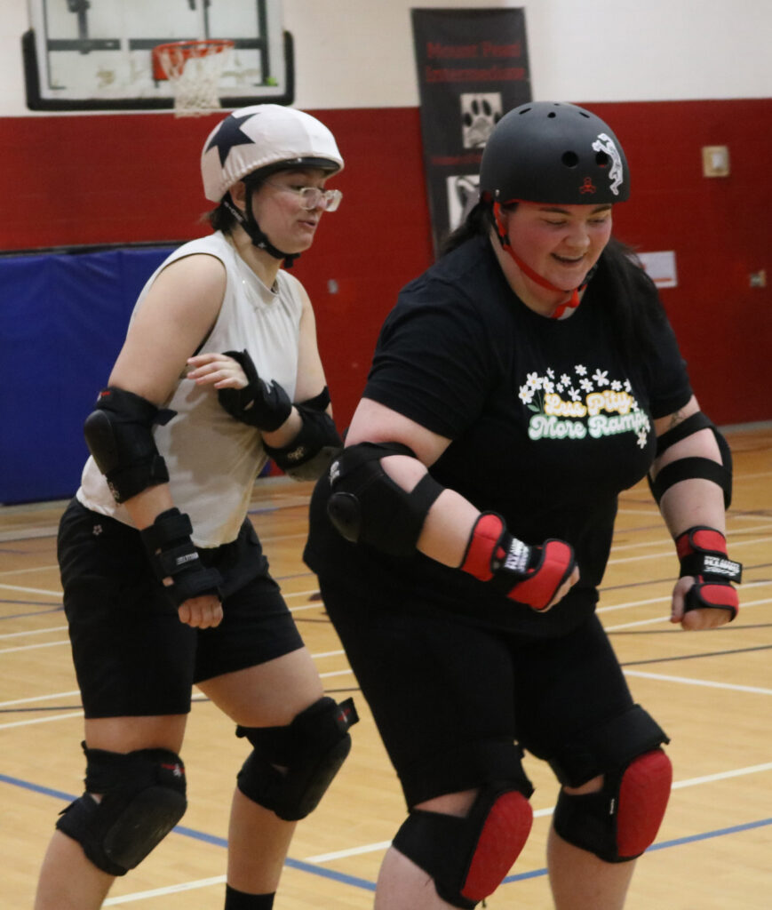 a girl with dark hair wearing all black, blocks a girls with short hair wearing all white.