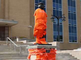 image shows John Cabot's statue in front of the confederation building wrapped in orange shirts and ties.