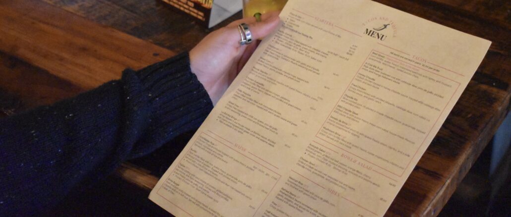 A customer at Cojones on Water Street reviews the menu. Cojones sales were down this August compared to the previous year even with the Canada games.