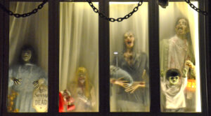 A display of Halloween decorations - a family of skeletons in the window of a house.