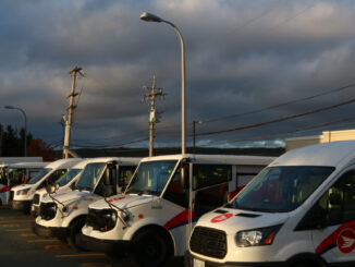 a line of canada post trucks park at sunset.