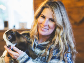 Julie Hollett, owner of Black Label Farm poses Honey, one of the goats in the cafe's painting program